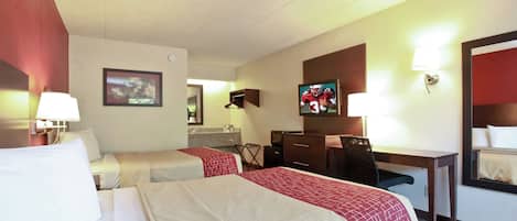 A hotel room with two beds, a desk, a television, and a mirror.