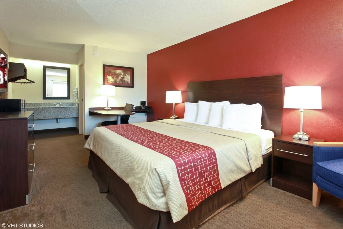 A hotel room with a bed, bedside tables, a desk, and a chair.