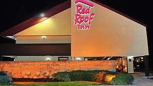 A Red Roof Inn with a prominent sign, stone facade, and a well-lit entrance.