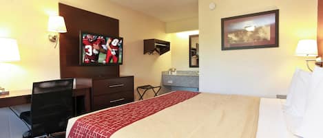 Ein Hotelzimmer mit Bett, Schreibtisch, Stuhl, Fernseher und Badebereich.