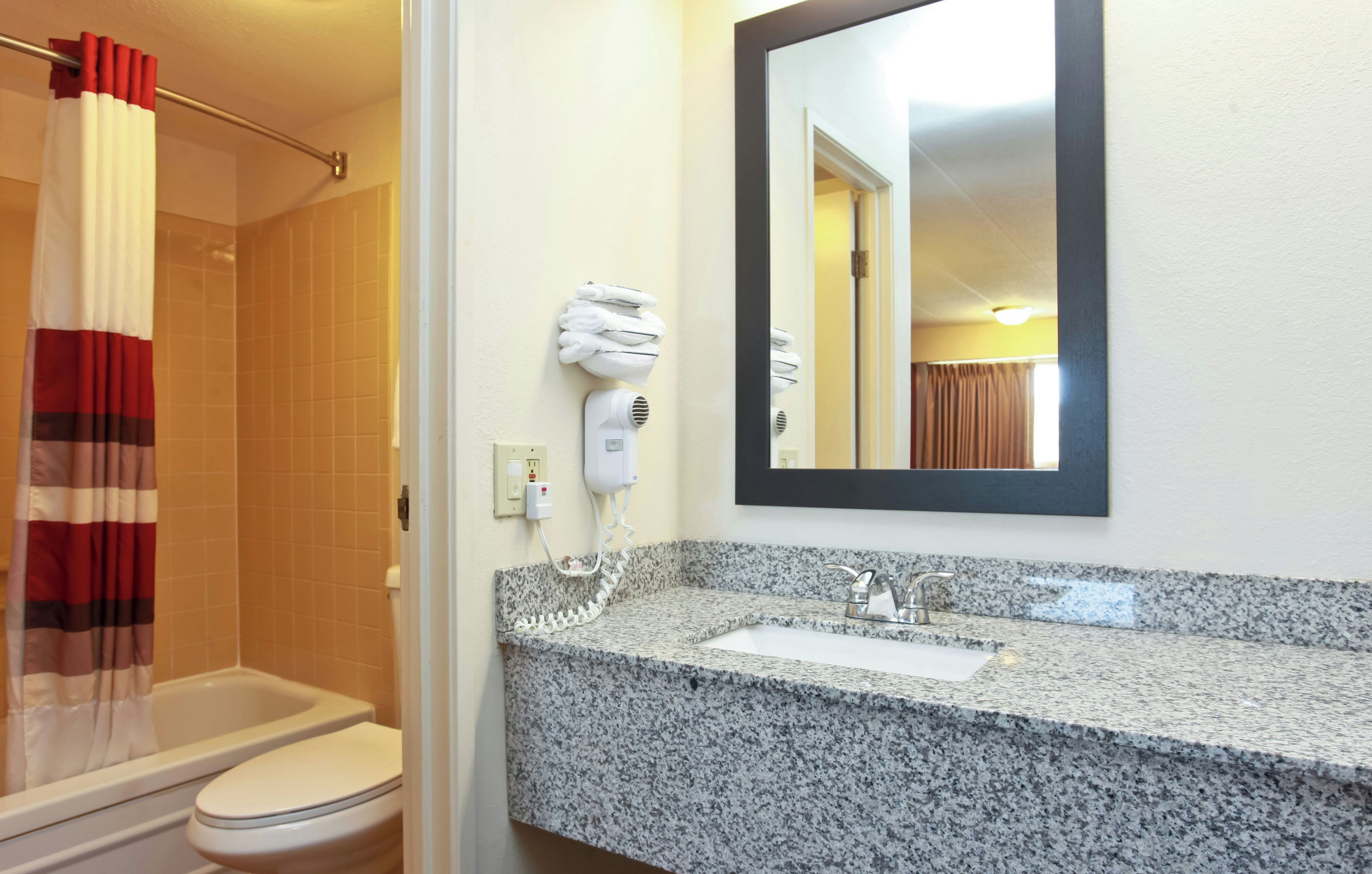 Un bagno con doccia, WC, lavandino e specchio.