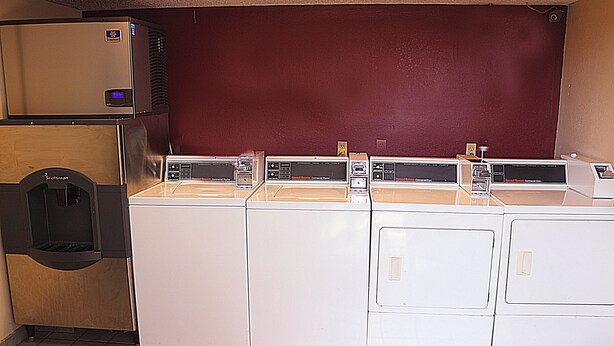 A laundry area with multiple washers and dryers, a water dispenser, and a red wall.
