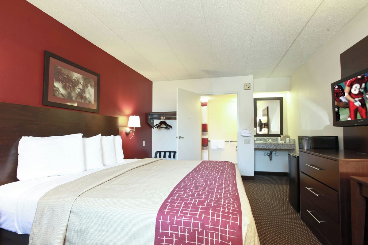 A hotel room with a bed, a television, a desk, and a bathroom.
