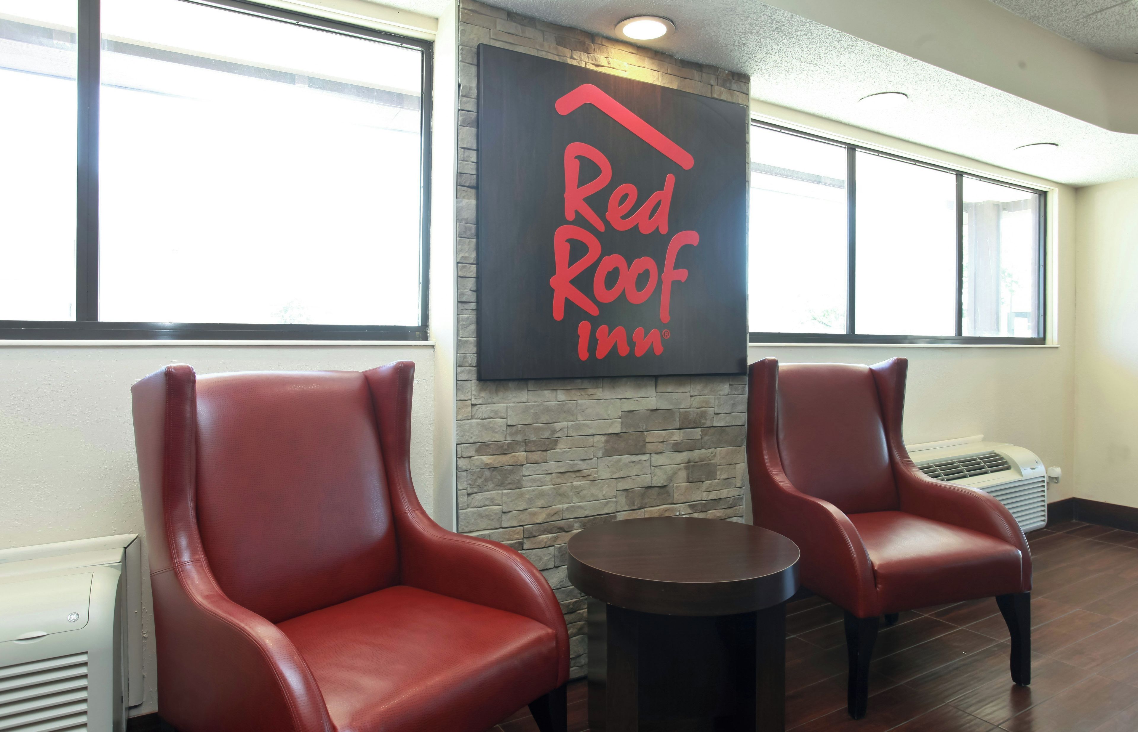 A Red Roof Inn interior with two leather chairs, a stone wall, and a large window.