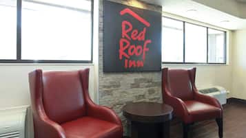A Red Roof Inn interior with two leather chairs, a stone wall, and a large window.