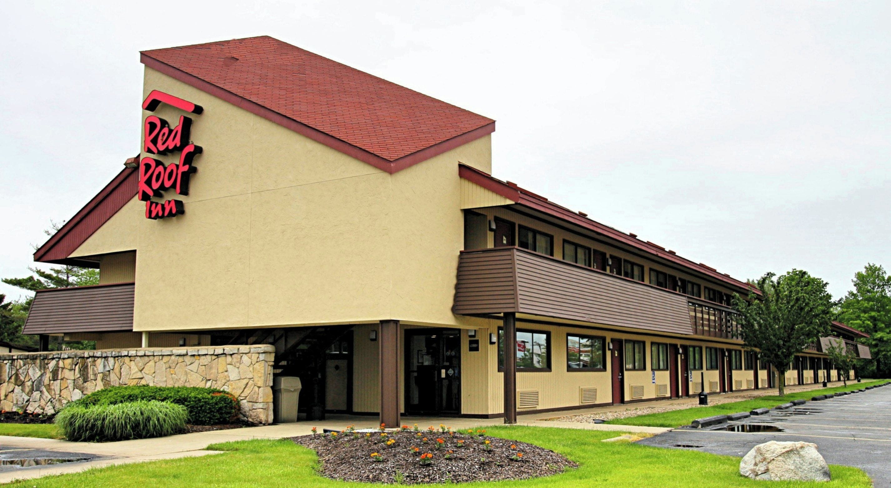 A Red Roof Inn with a stone facade, a flat roof, and a parking lot.