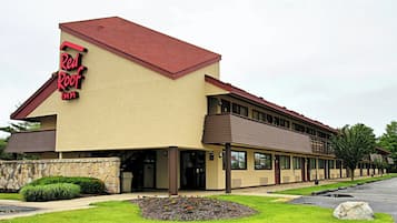 A Red Roof Inn with a stone facade, a flat roof, and a parking lot.