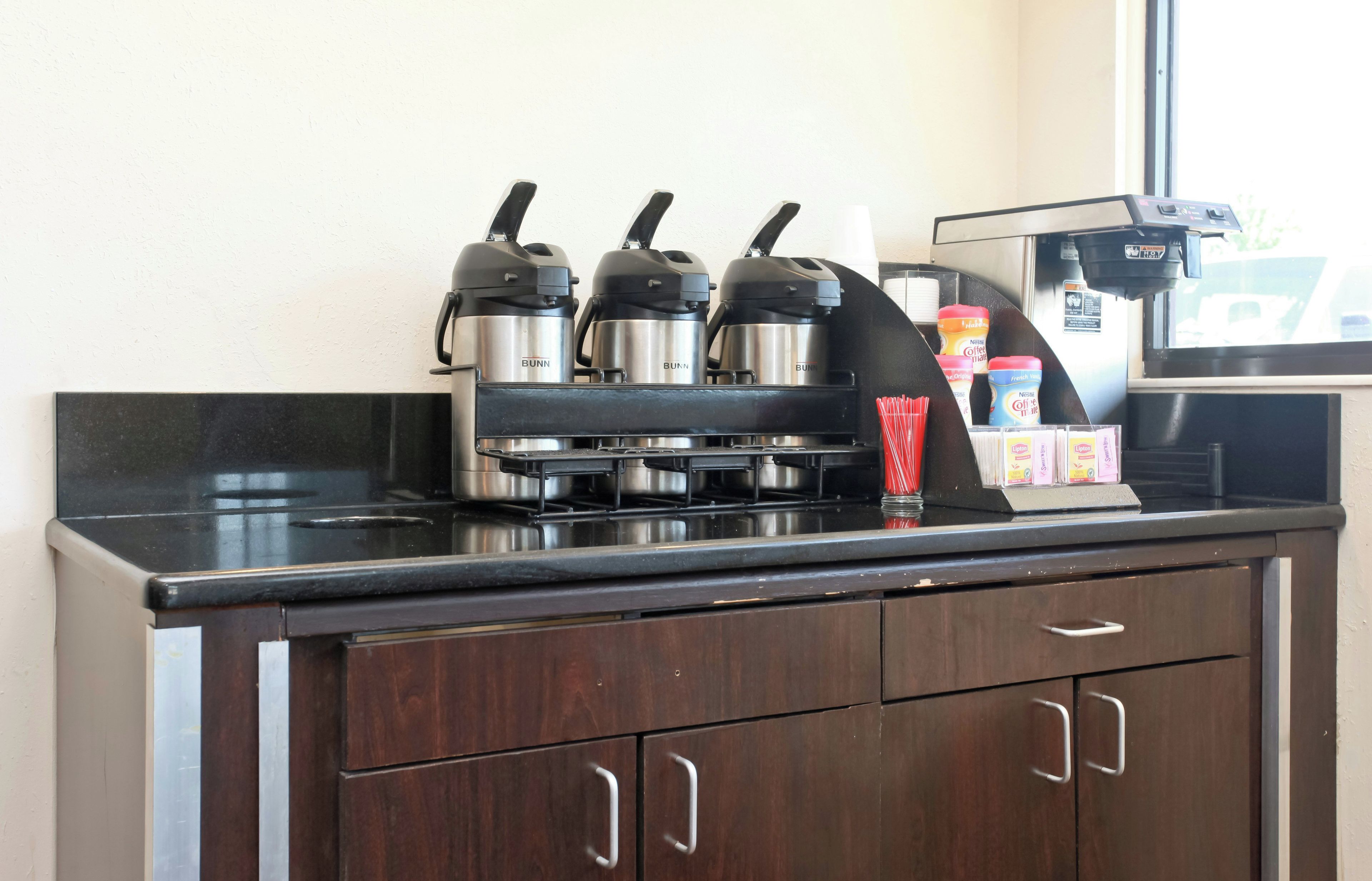 Una kitchenette con una cafetera, tres picos para hervir agua y un dispensador de café.