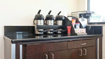 Una kitchenette con una cafetera, tres picos para hervir agua y un dispensador de café.