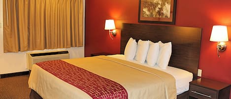 Una habitación de hotel con una cama, dos lámparas de noche, un calefactor, una ventana con cortinas y un cuadro en la pared.