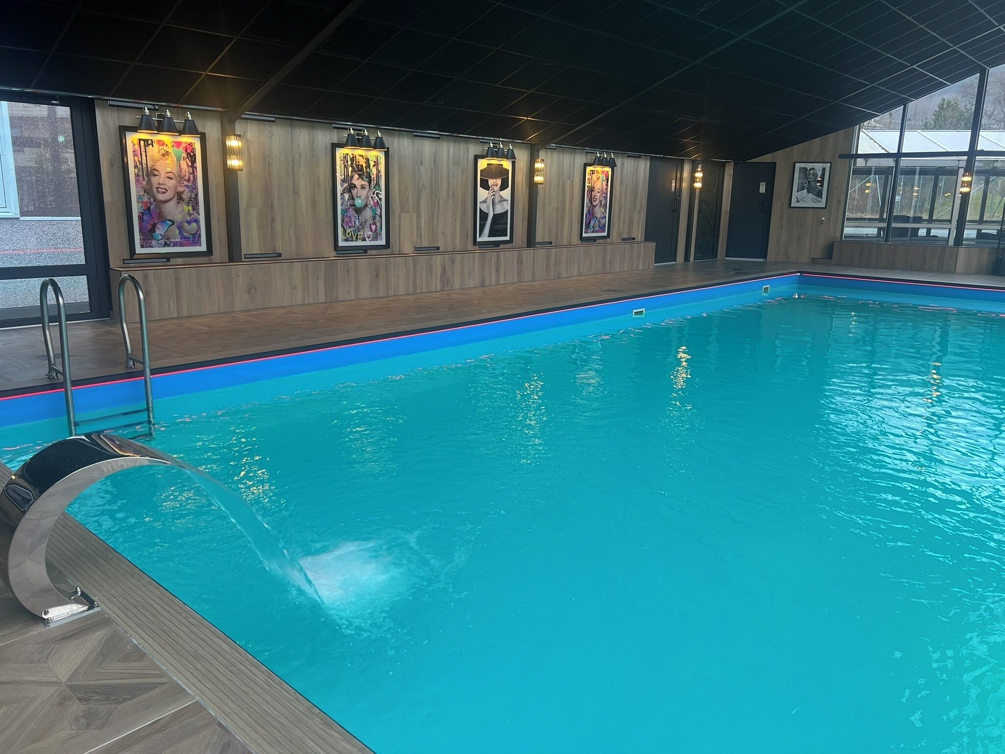 An indoor swimming pool with wooden walls and framed artwork.
