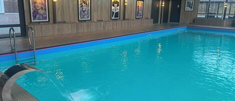An indoor swimming pool with wooden walls and framed artwork.