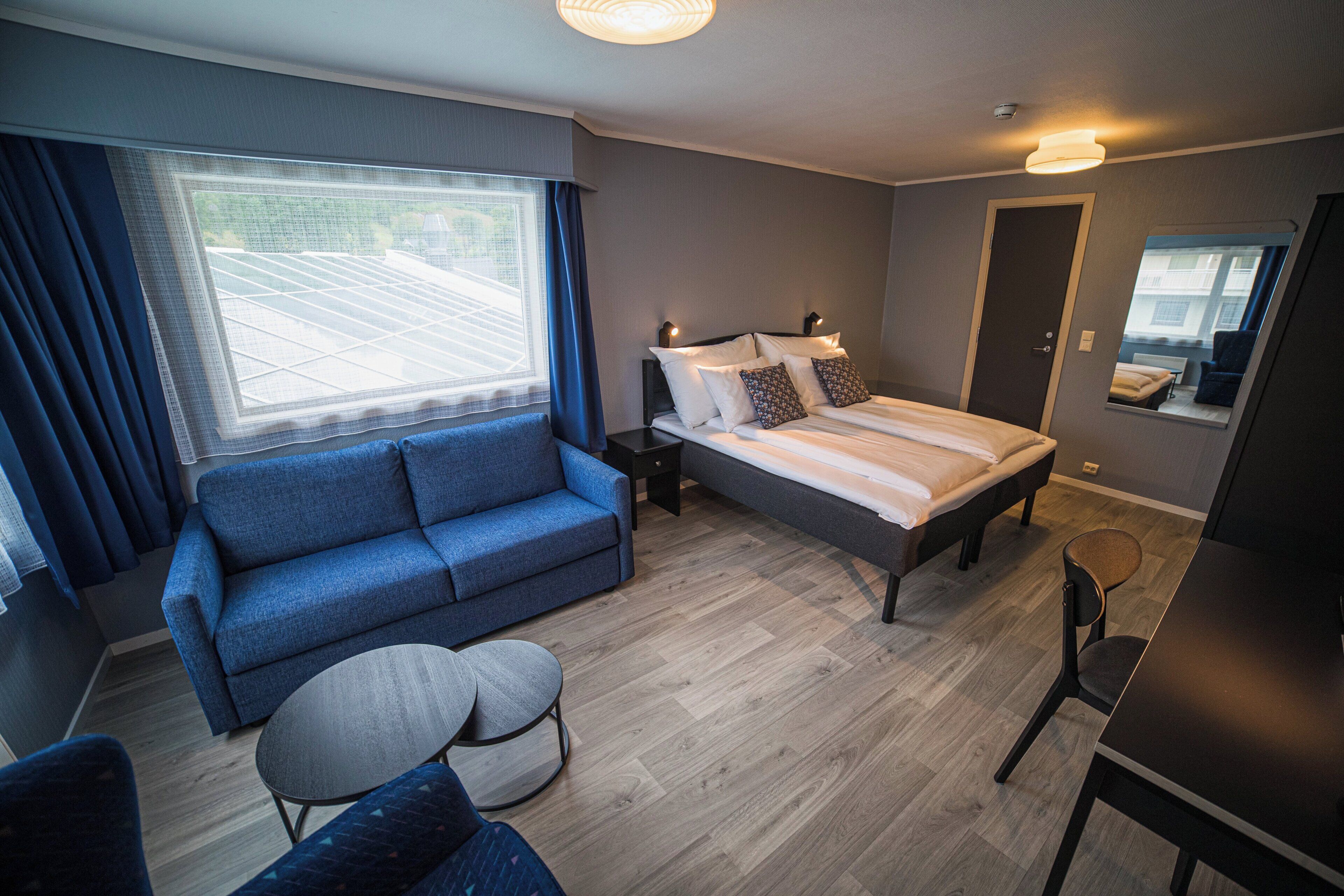 A modern bedroom with a bed, a sofa, a small round table, and a desk.