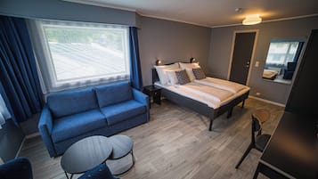 Et moderne soveværelse med seng, sofa, lille rundt bord og skrivebord.
