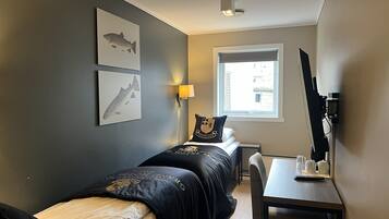 Ein Hotelzimmer mit zwei Betten, einem Schreibtisch, einem Stuhl, einer Lampe und einem Fenster mit Blick.