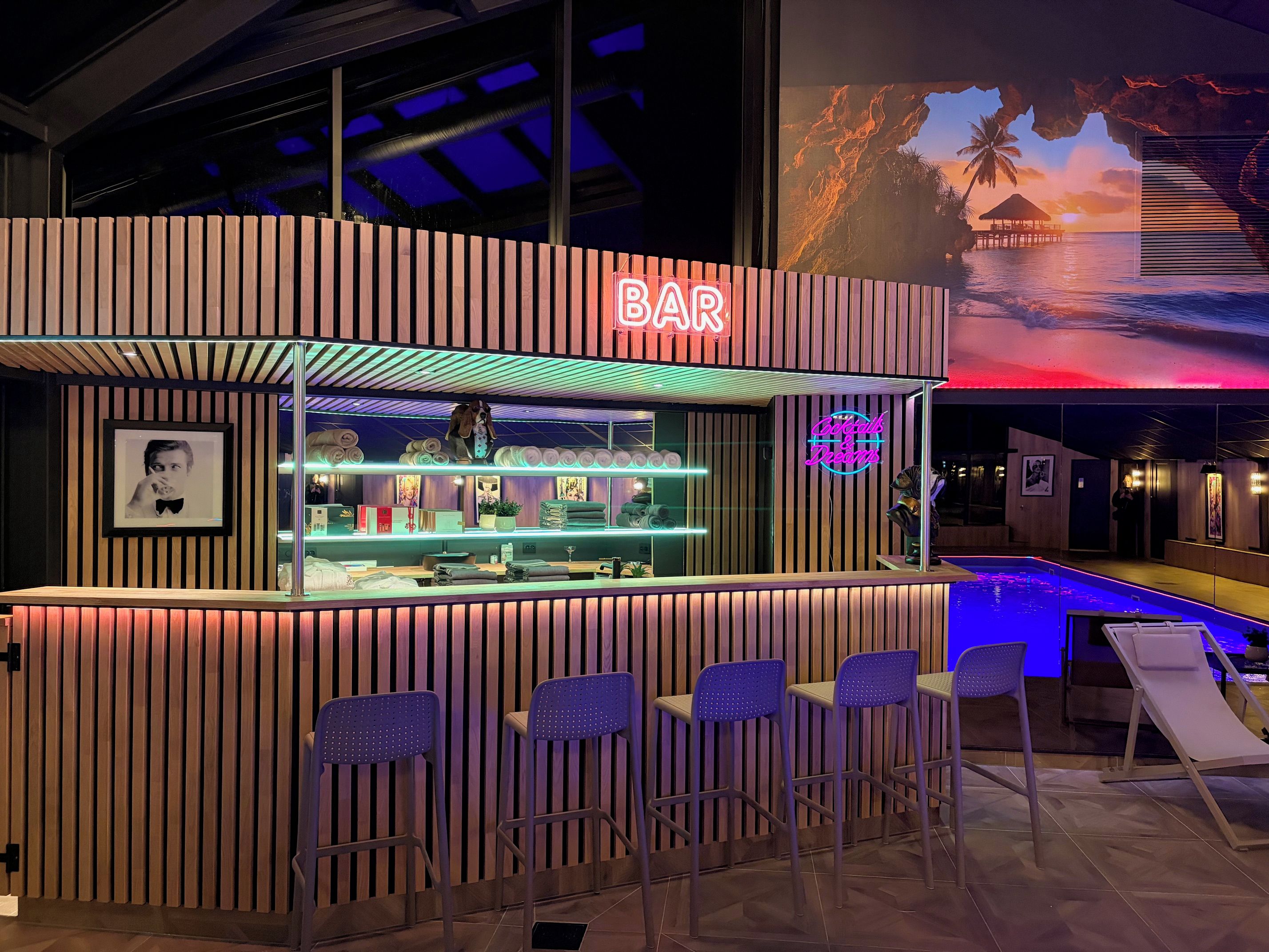 Een bar met neonreclame, zitplaatsen en uitzicht op het zwembad.