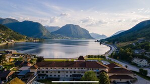 Un grand immeuble à étages, doté d’un parking et offrant une vue sur un lac entouré de montagnes.