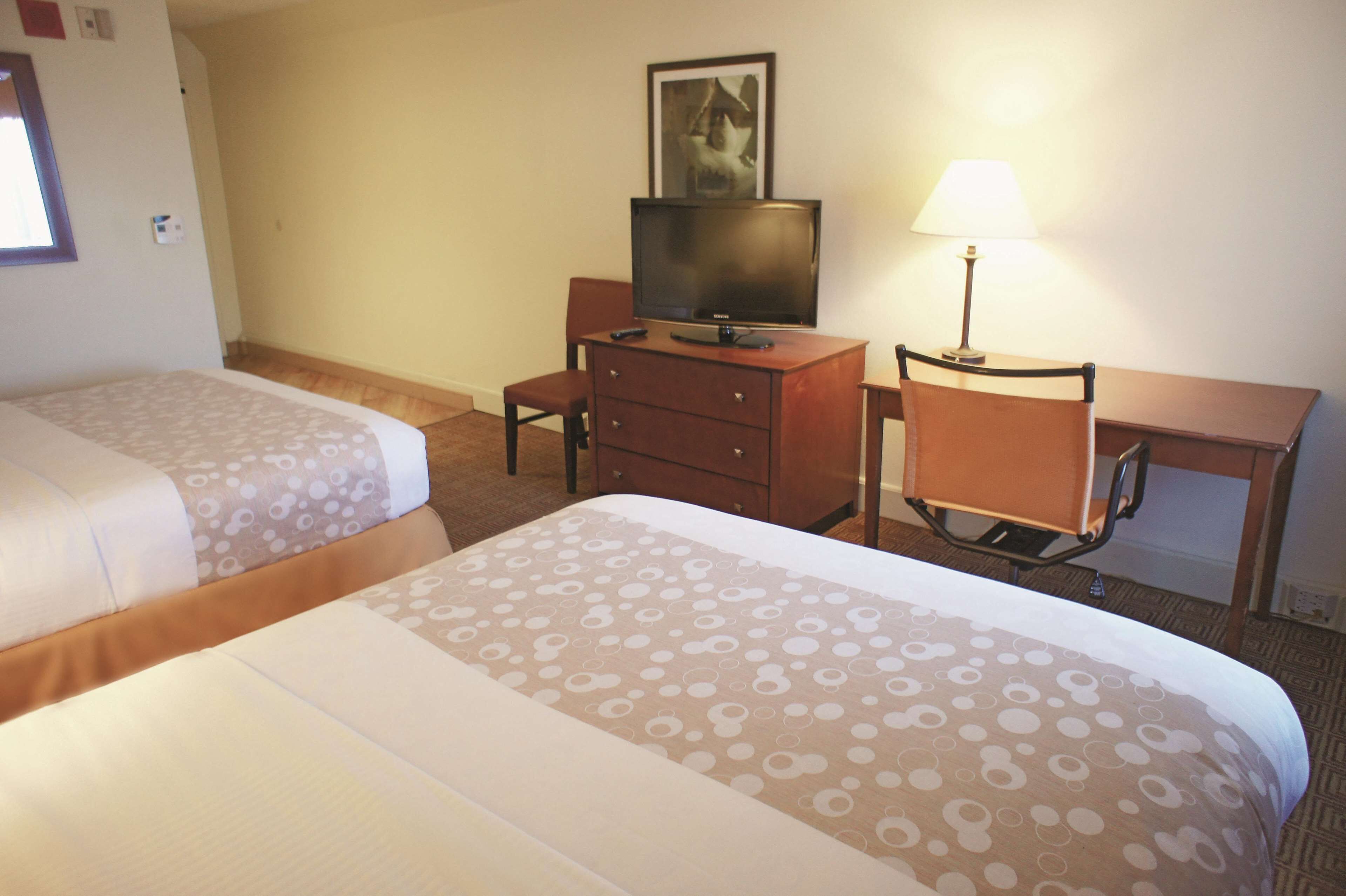 Une chambre d’hôtel avec deux lits, une télévision, un bureau et une lampe.