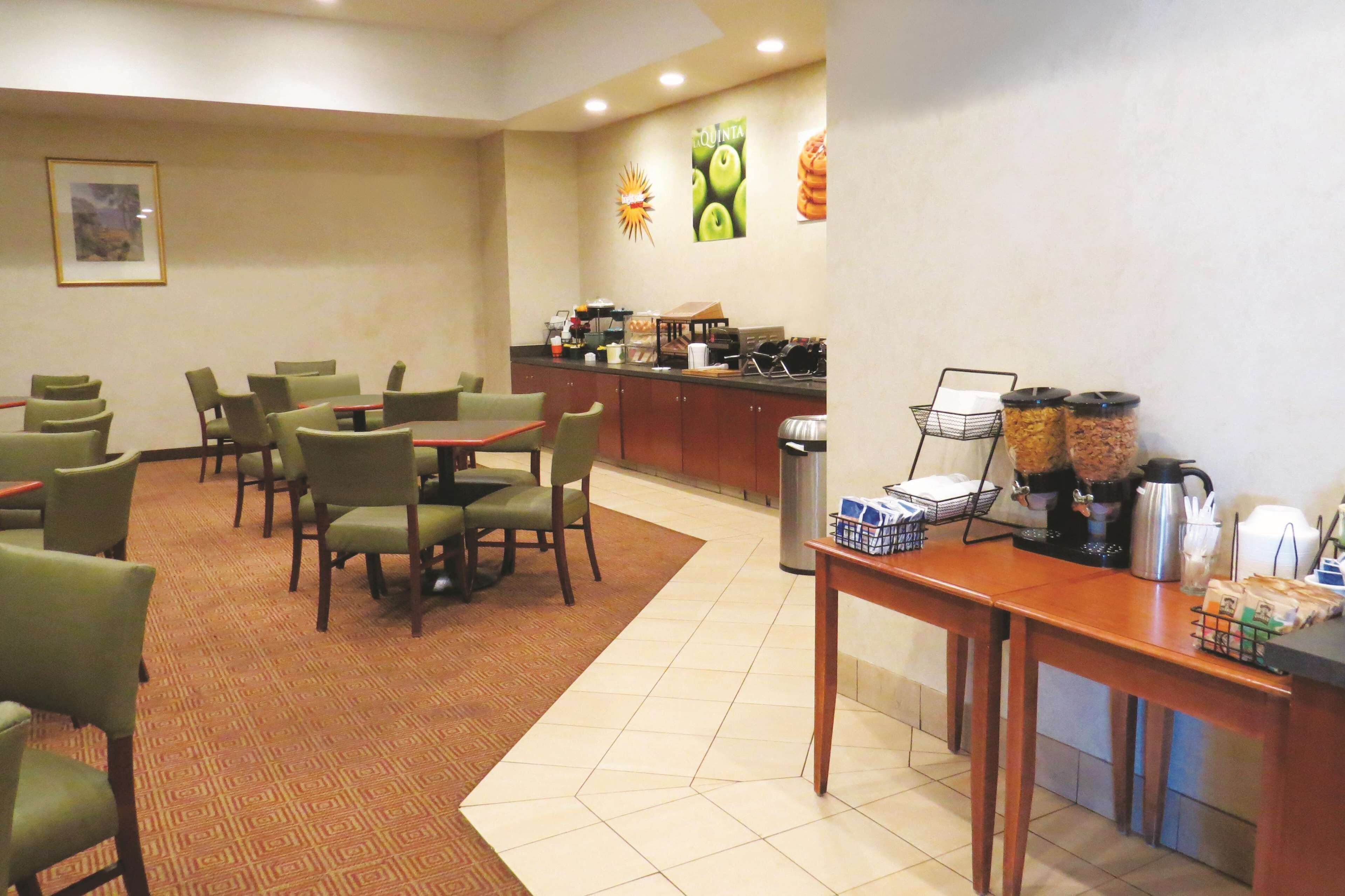 Habitación de hotel con zona de comedor, estación de café y un basurero.