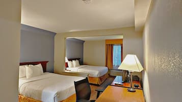 Une chambre d’hôtel avec deux lits, un bureau, une chaise et une lampe.