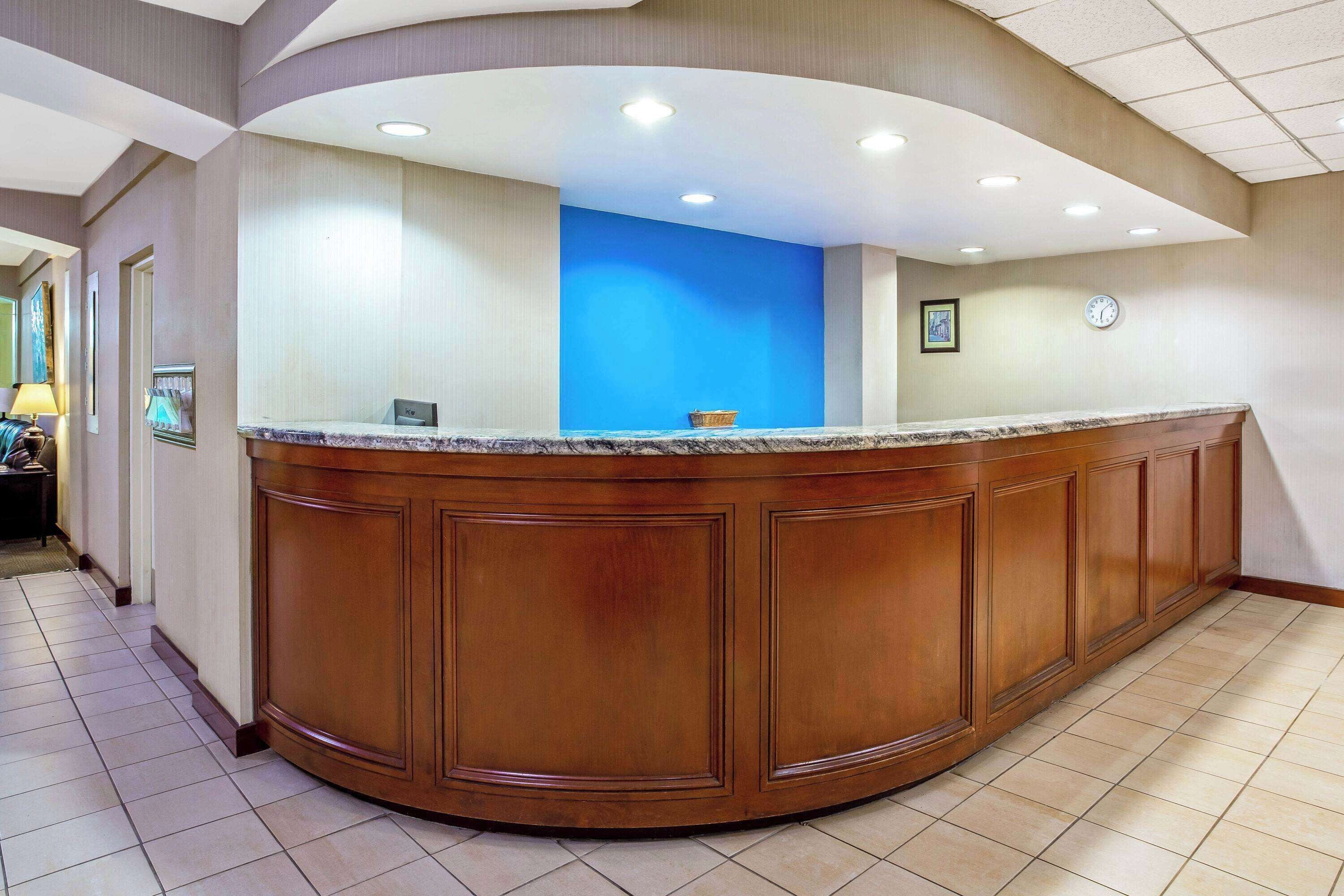 Un'area reception con un bancone in legno curvo, una parete d'accento blu e una sveglia appesa al muro.