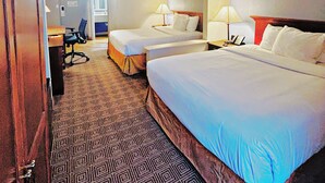 Ein Hotelzimmer mit zwei Betten, einem Schreibtisch, einem Stuhl und einem gemusterten Teppich.