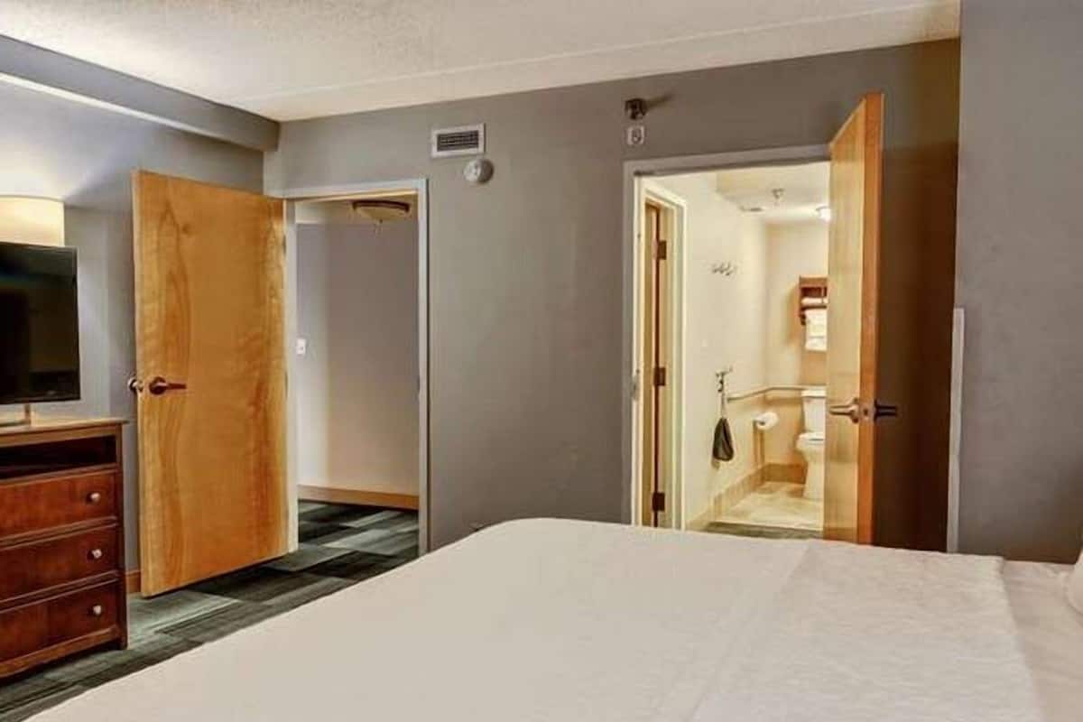 Un dormitorio con una cama grande, un armario de madera y una televisión.