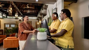 Uma área de recepção com balcão, computador e planta em vaso.