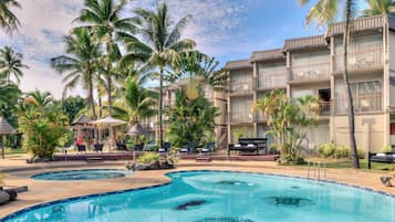 Un resort con piscina, palme e un edificio con balconi.