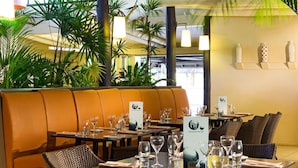 Um restaurante com área de assentos em cabines, mesas montadas com copos de vinho e um suporte para cardápio.