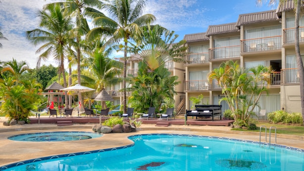 Um hotel com piscina, palmeiras e áreas de estar ao ar livre.
