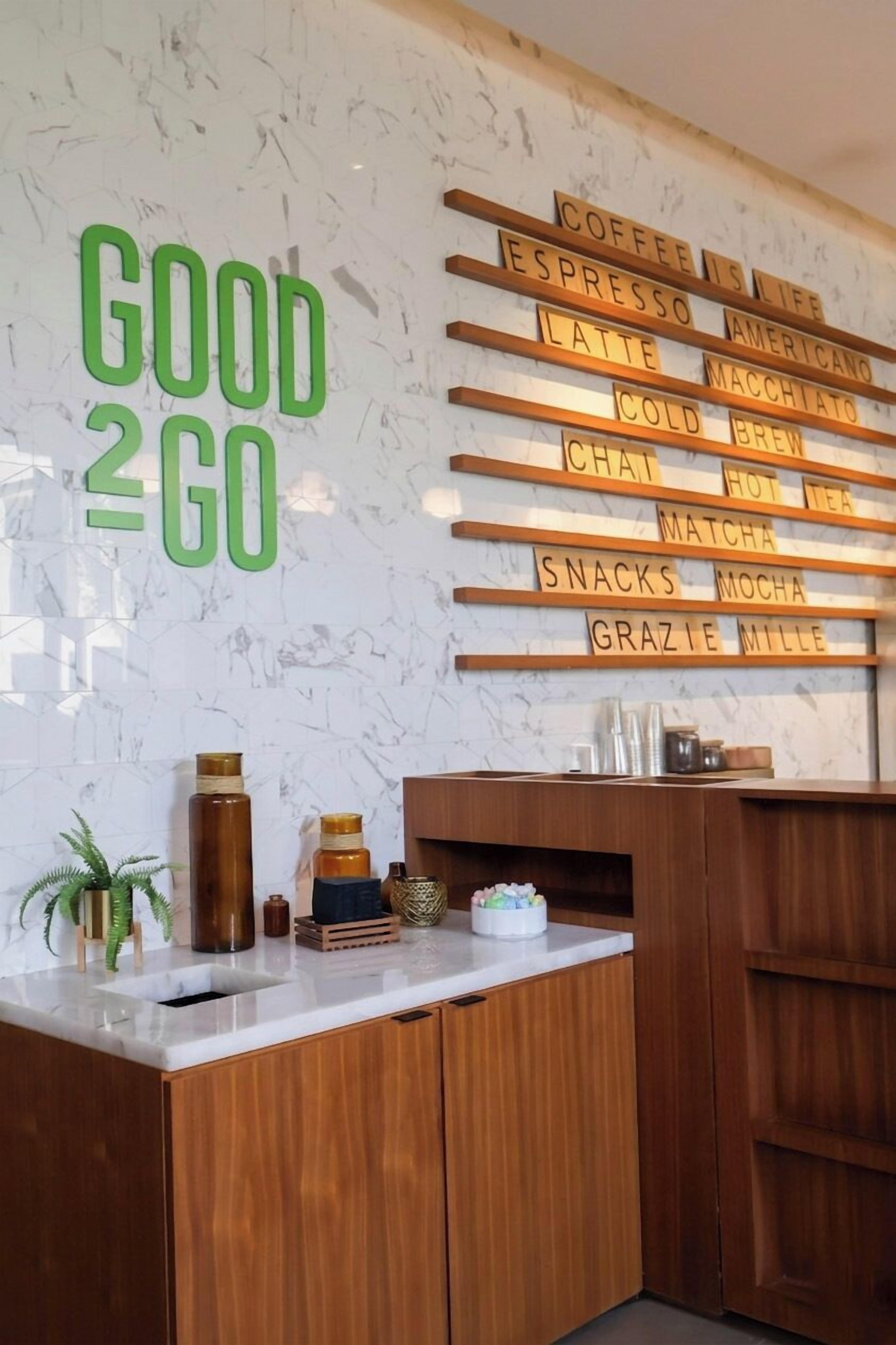 A wall with coffee-related words and a 'GOOD 2 GO' sign.