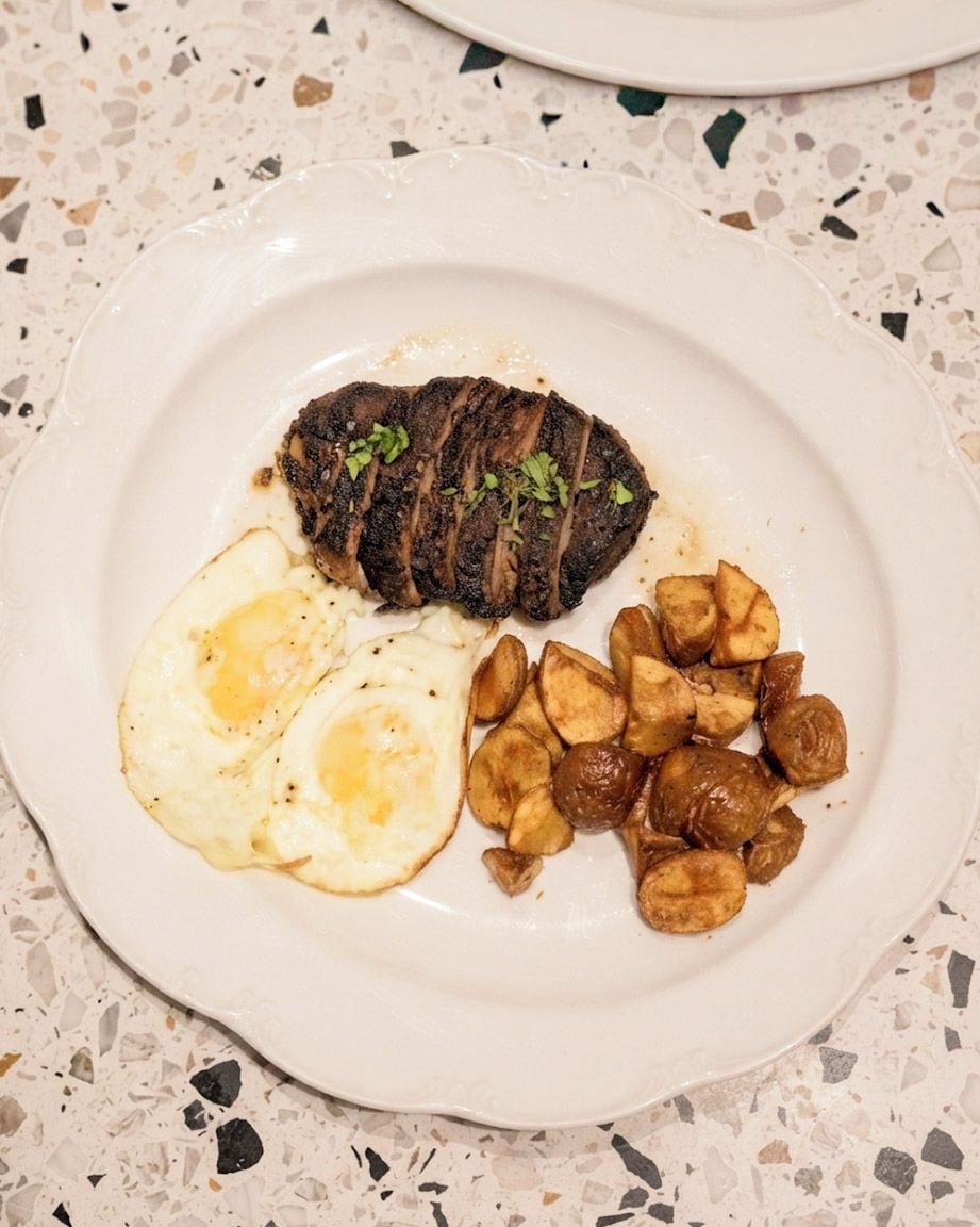 A plate with a steak, two fried eggs, and roasted potatoes.
