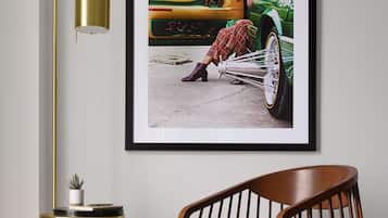 Fotografía enmarco de un coche antiguo, una mujer, una lámpara de pie dorada y una silla de madera en una habitación.