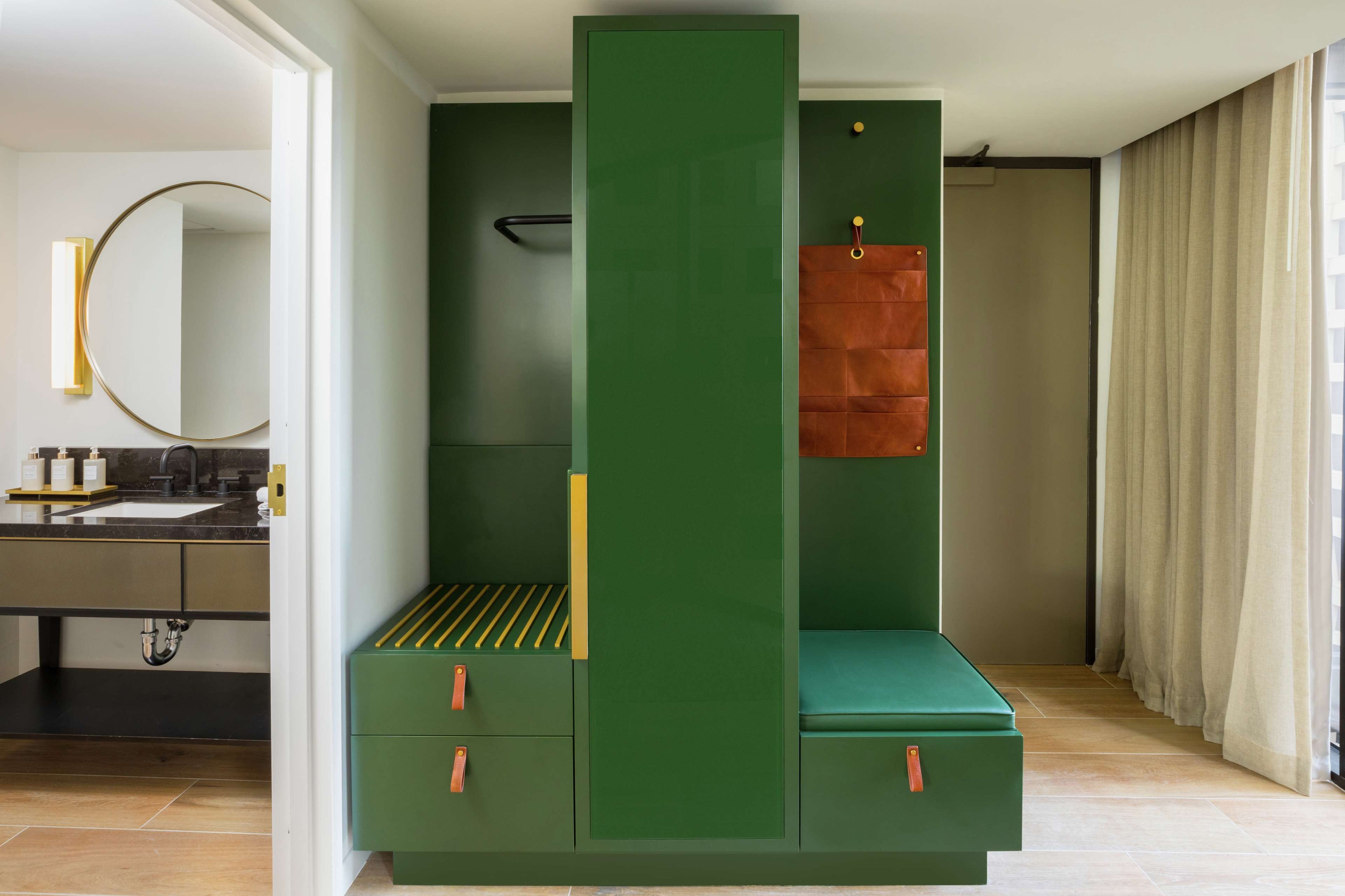 A modern bathroom with a green vanity, a mirror, and a towel rack.