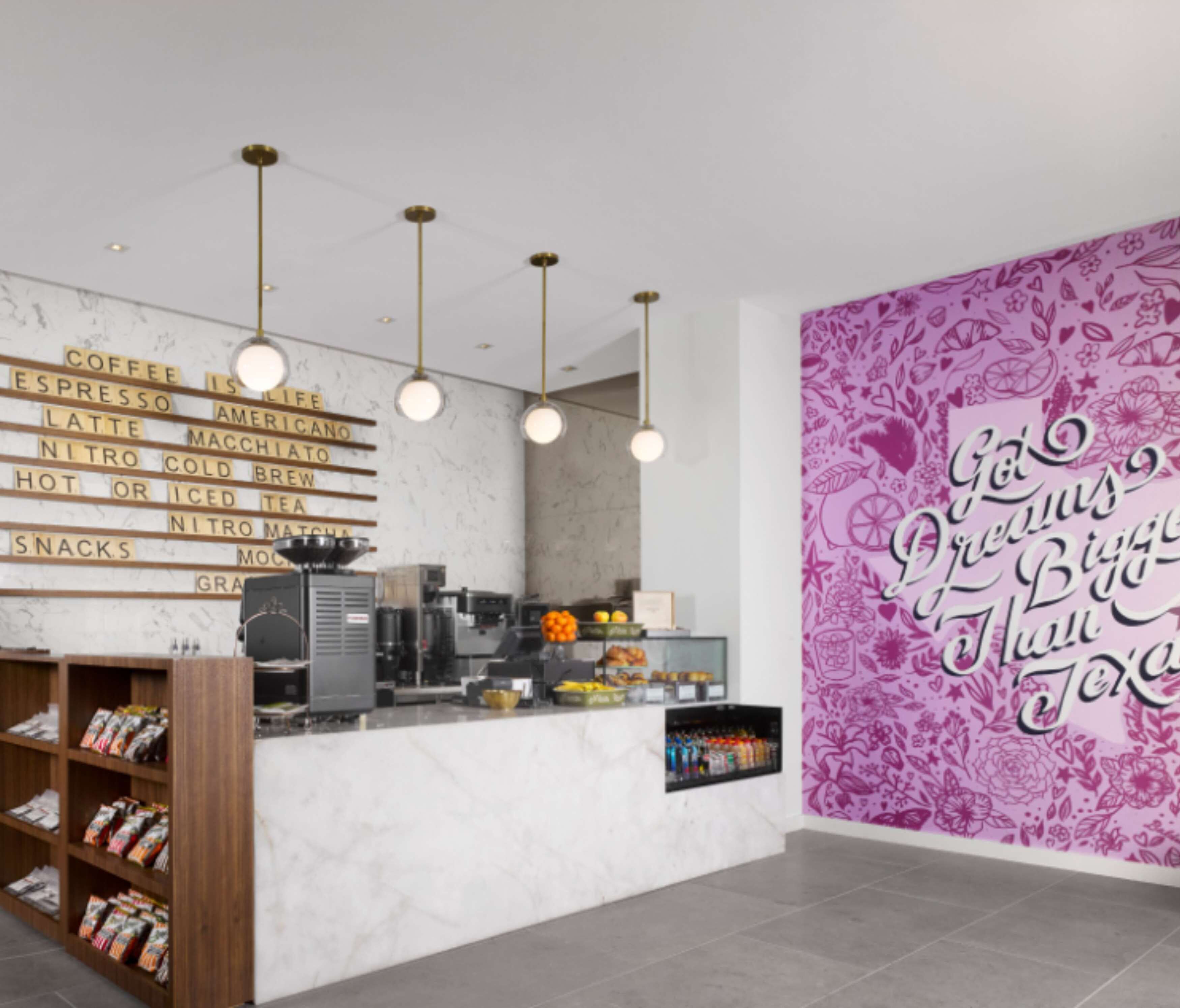 L’intérieur d’un café moderne, avec un comptoir en marbre, un menu de cafés et un mur orné d’un motif floral.