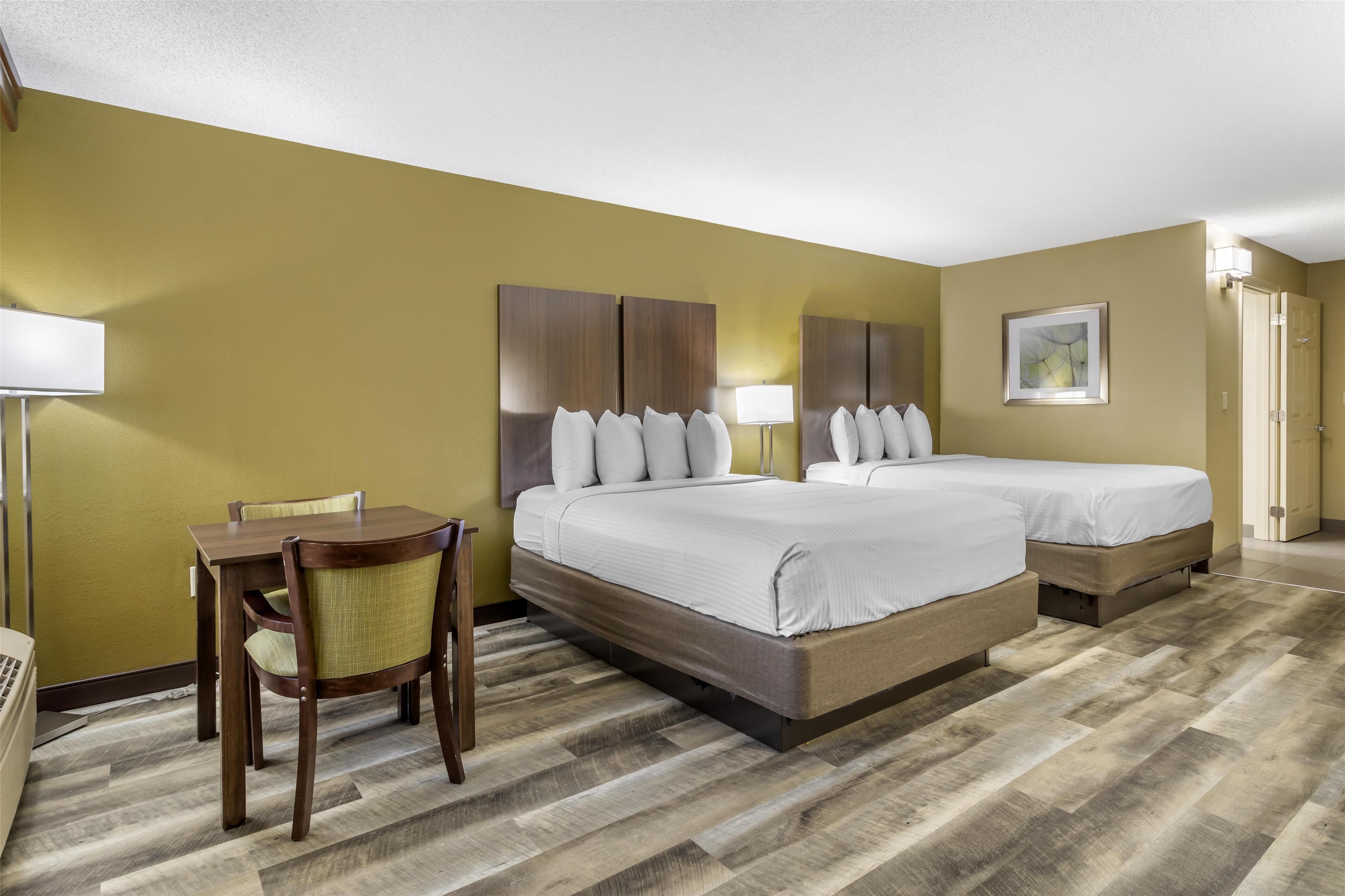 A hotel room with a bed, a desk, and a chair.