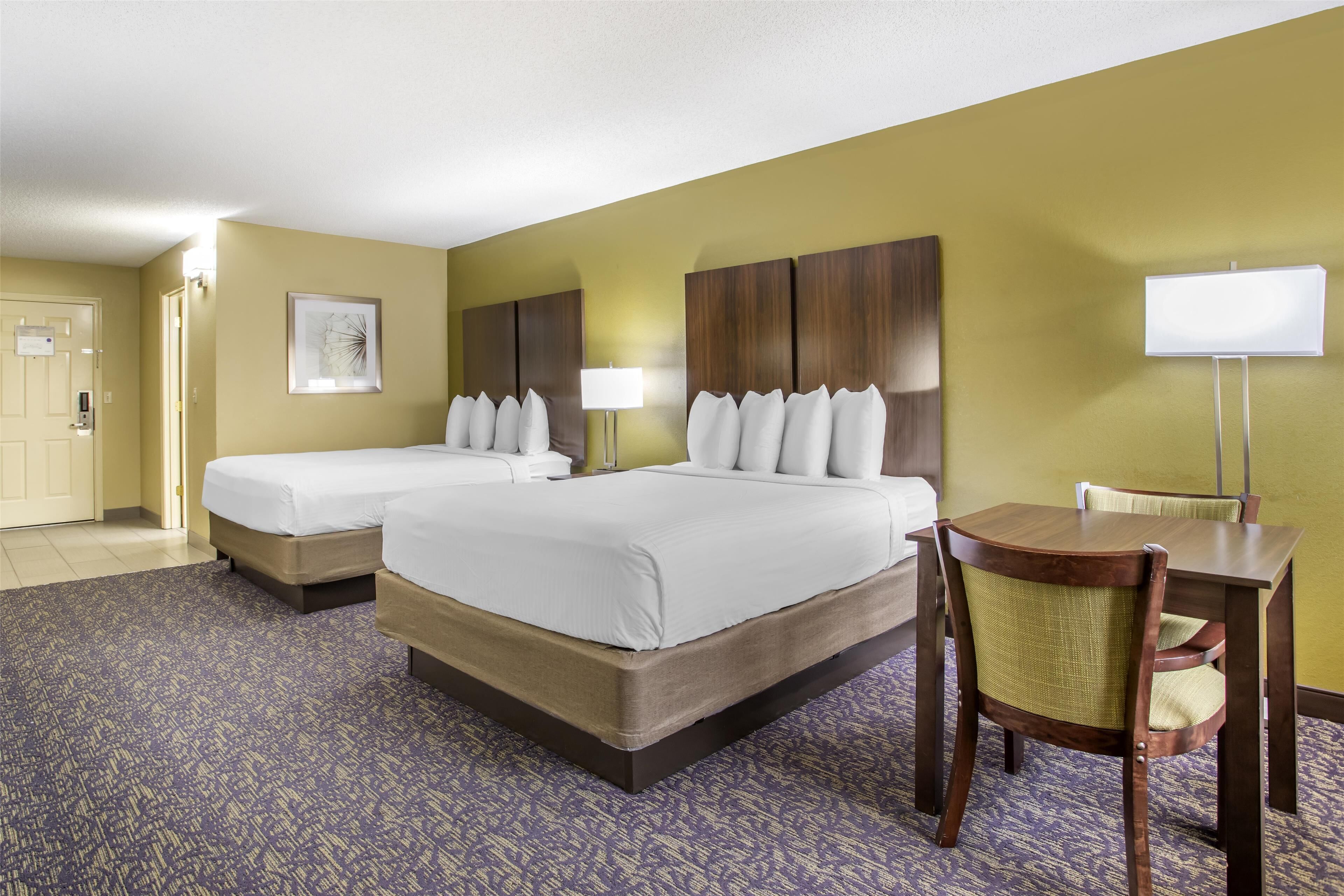 Une chambre d’hôtel avec deux lits, un bureau et une chaise.