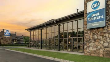 A Best Western Plaza Inn with a stone facade and large glass windows reflecting the interior.