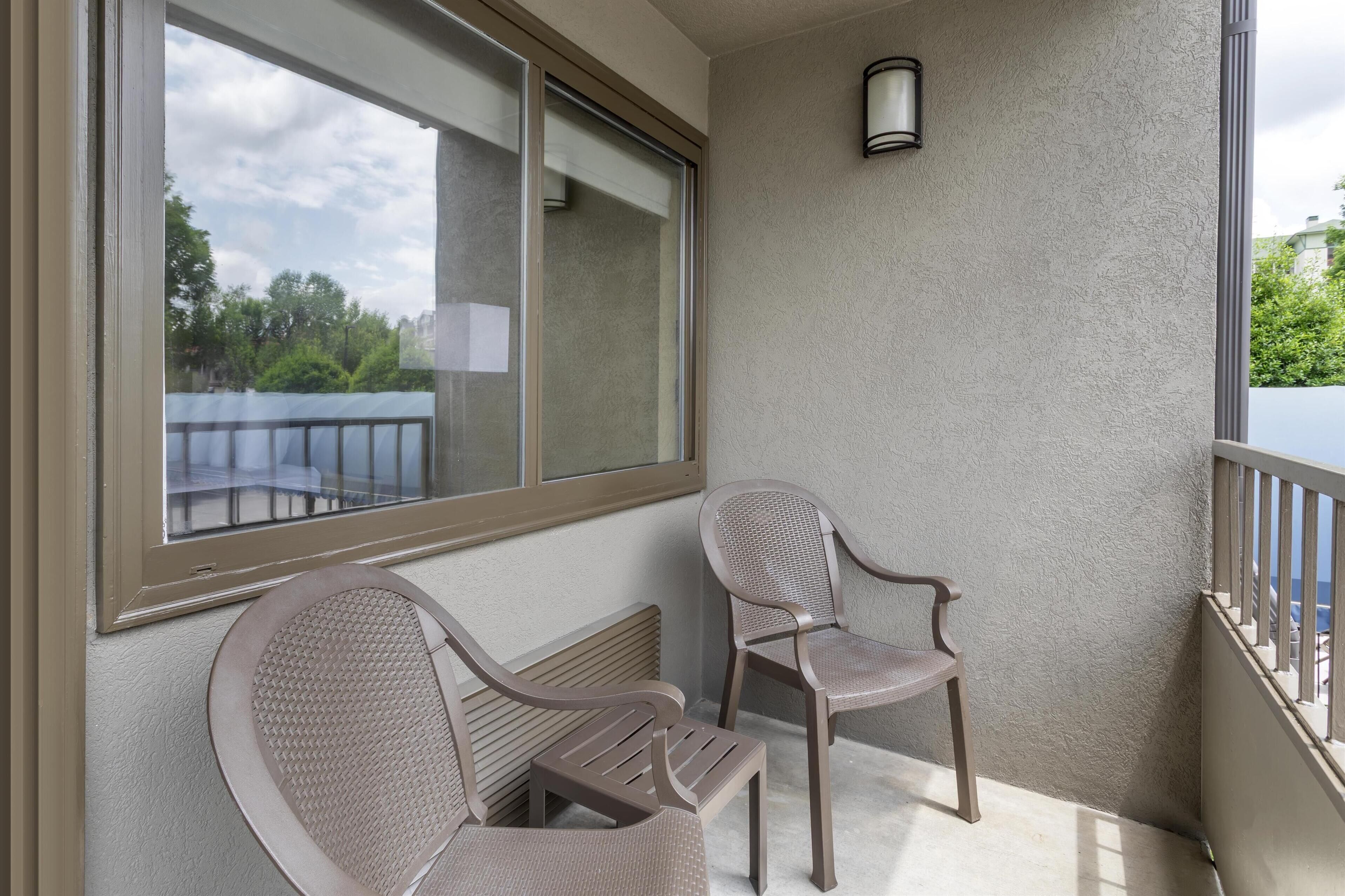 A balcony with two chairs and a large window.