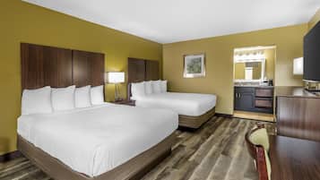 Een hotelkamer met twee bedden, een bureau, een stoel, een spiegel en een kitchenette.