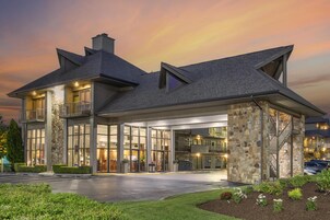 A modern hotel with a stone facade, large glass windows, and a covered entrance.