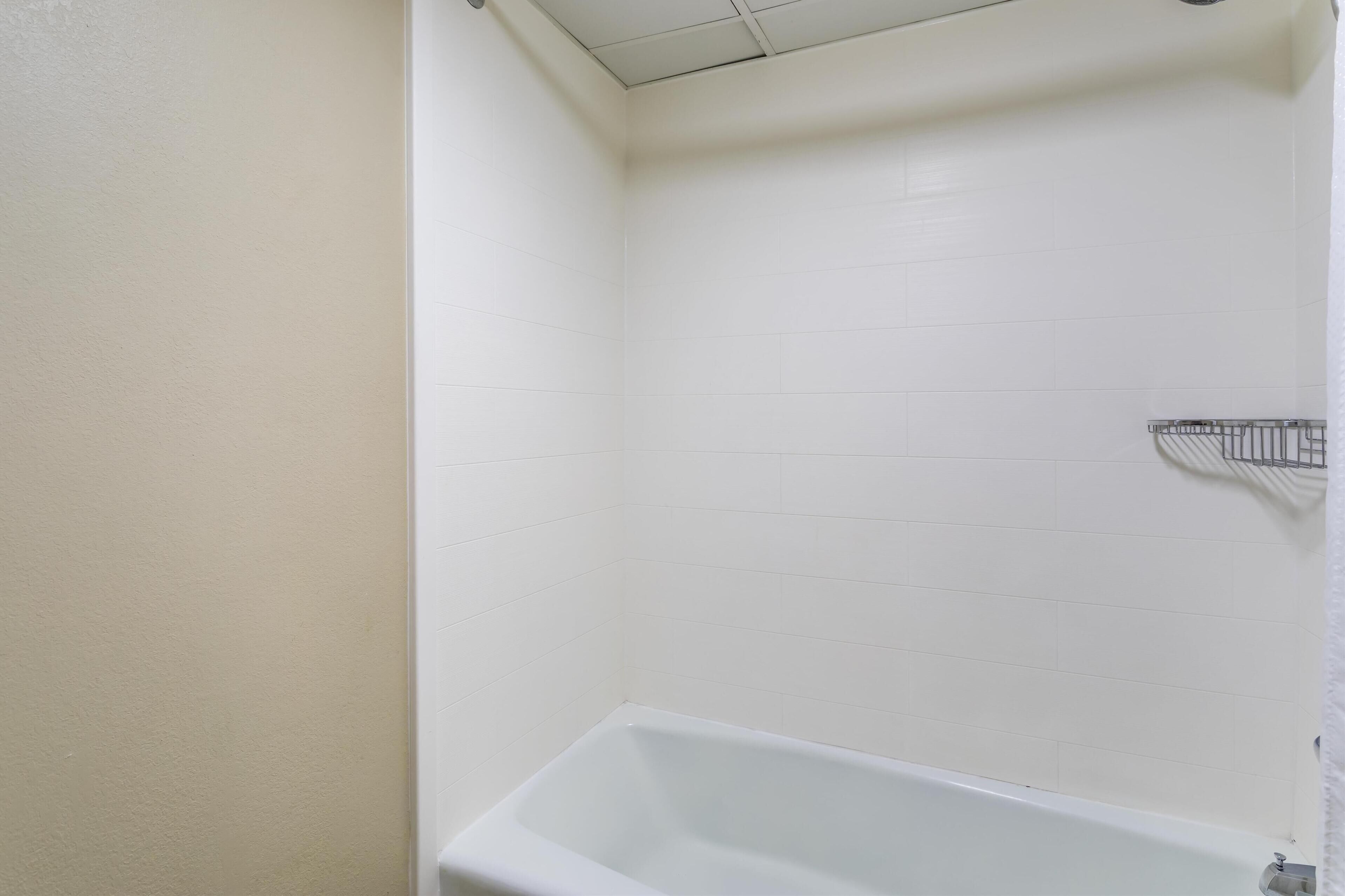 Ein Badezimmer mit weiß gefliesten Wänden und einer weißen Badewanne.