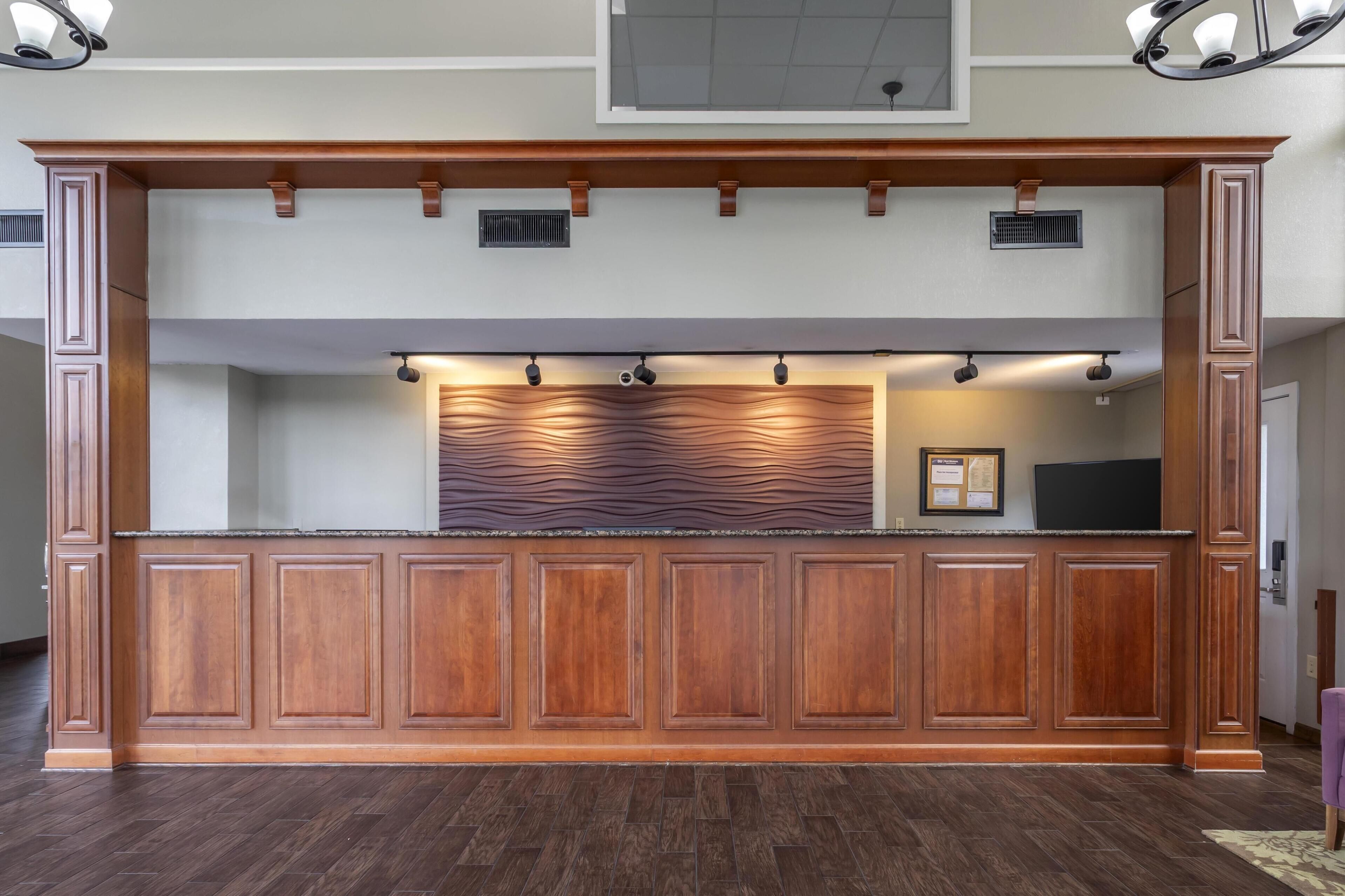 A wooden reception desk with built-in lighting and a decorative wall panel.