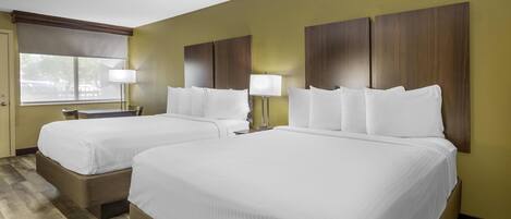 A hotel room with two beds, a window with a view, and a lamp on each side.