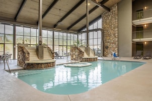 An indoor swimming pool with stone steps and lounge chairs.