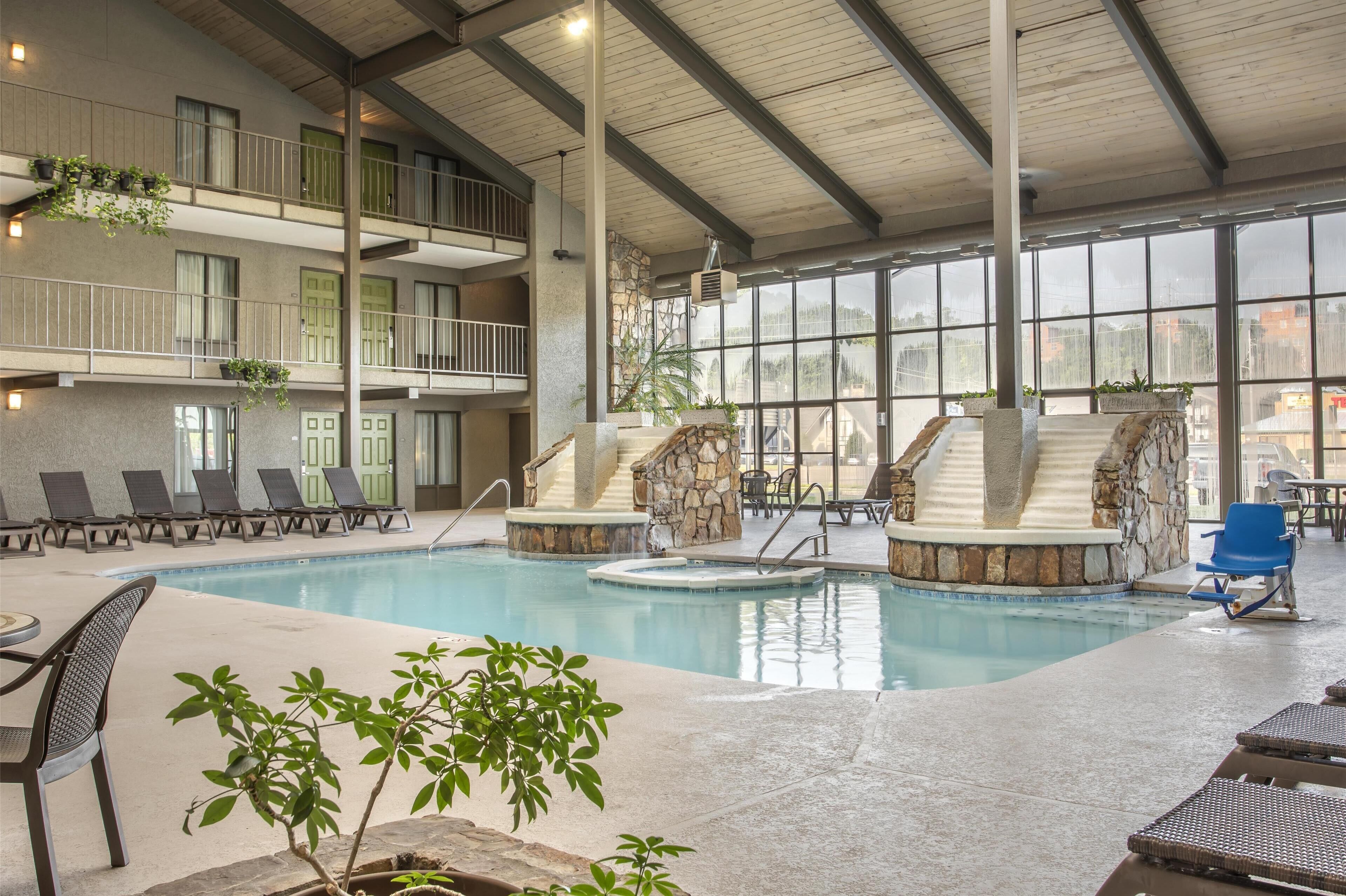 An indoor swimming pool with multiple levels, stone steps, and lounge chairs.