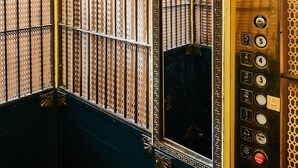 Ein Elevatoreninneres mit aufwendigen Metallverkleidungen und einer Spiegelwand.