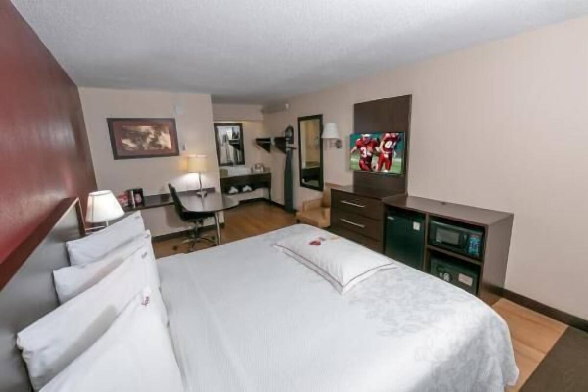 Ein Hotelzimmer mit Bett, Schreibtisch, Stuhl, Fernseher und Kommode.