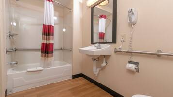 A bathroom with a bathtub, a sink, a toilet, a mirror, and a shower curtain.